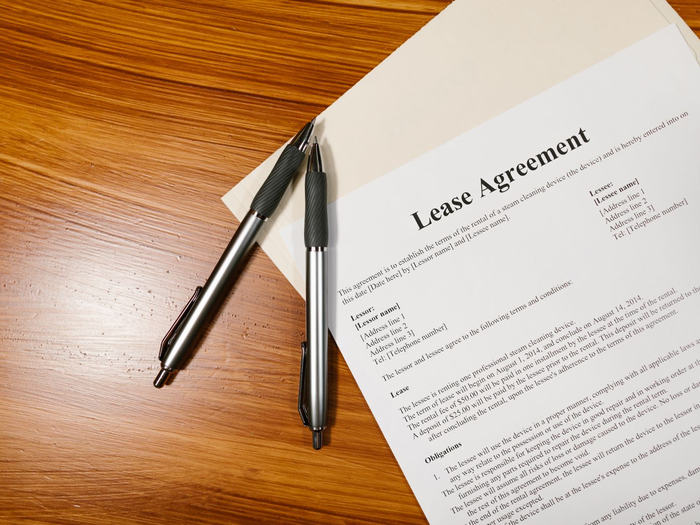 High angle view of a lease agreement and pens on a wooden desk.