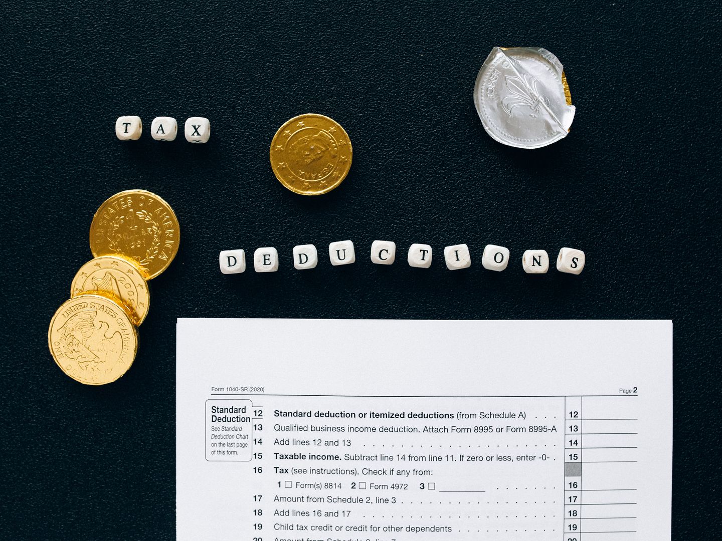 Image of tax deductions concept with coins and tax form on black background.