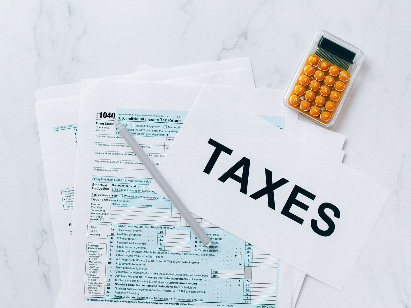 Top view of tax forms, a calculator, and pen for tax preparation.