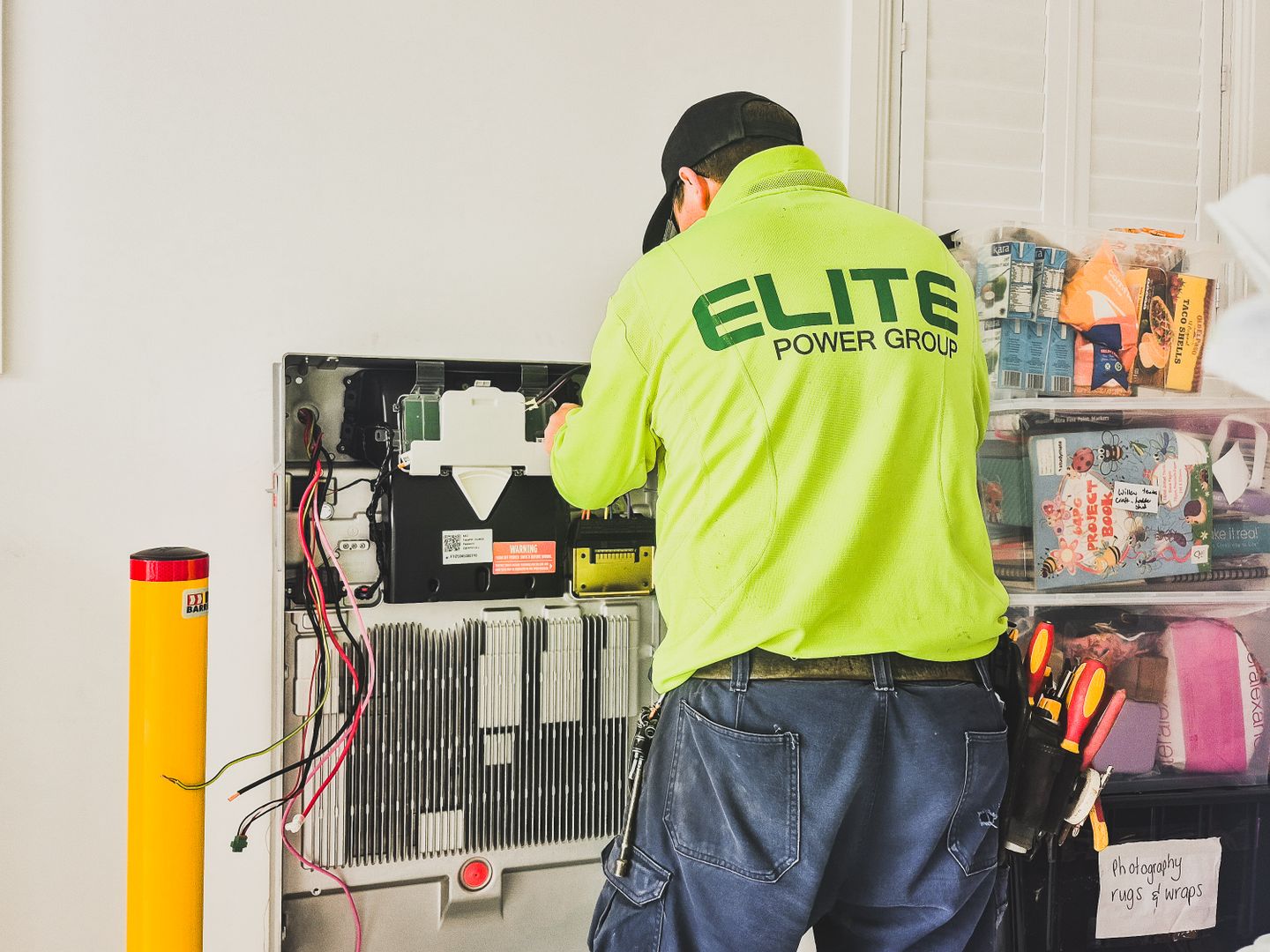 A technician from Elite Power Group installing a home battery system indoors in New South Wales, Australia.